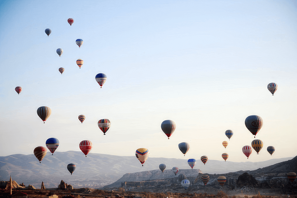 Hot air balloons over a mountain landscape at golden hour.