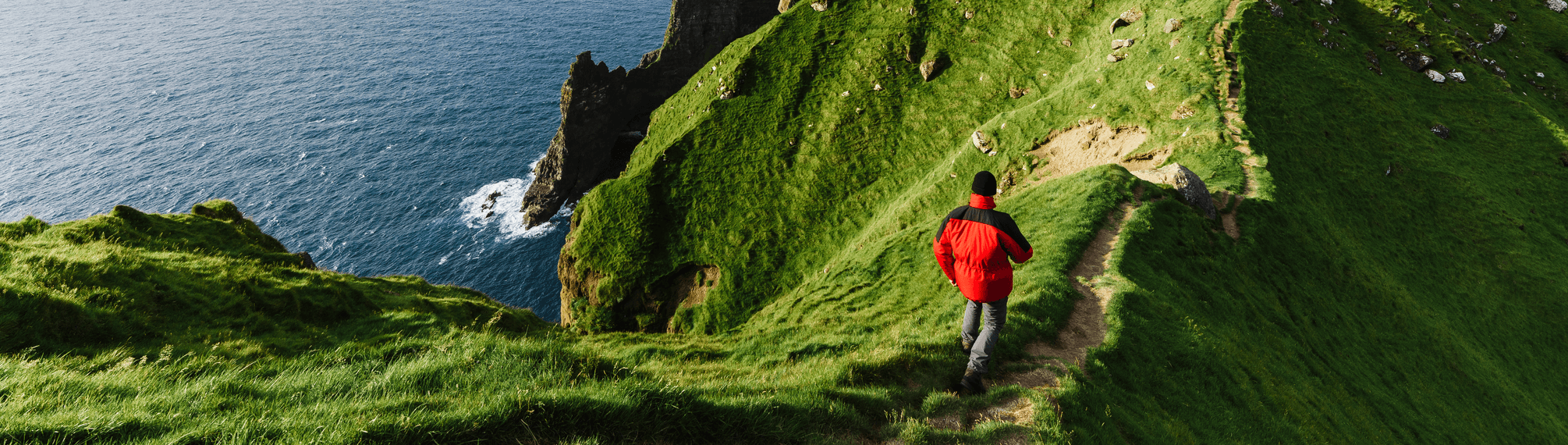 hiker on path in grass near sea side